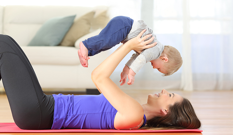 Mother holding baby on yoga mat