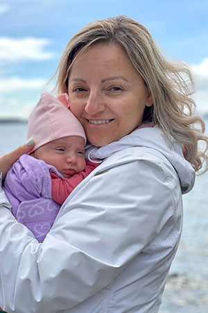 Agota holding her baby on a beach.