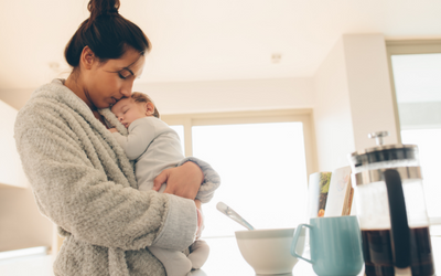 Woman in bathrobe holds newborn.