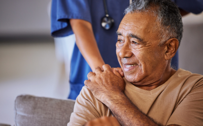 Older man holds the hand of a nurse.