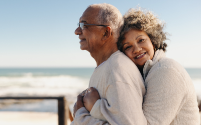 Older couple embrace on beach.