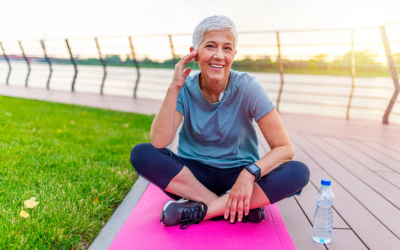 Older woman sits on pink yoga mat.