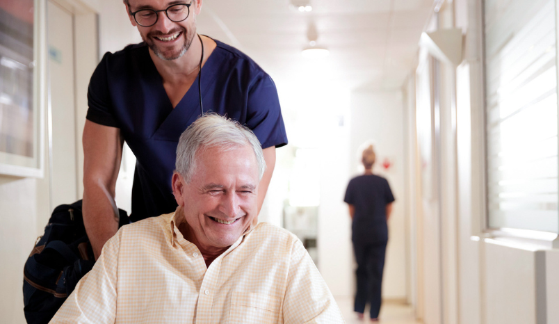 Nurse pushes patient in wheelchair.