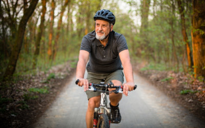 Older man rides mountain bike on forest trail.