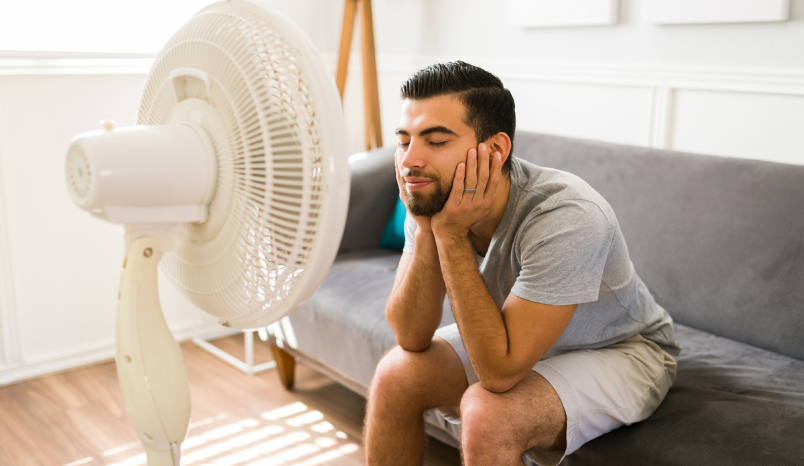 Man cools off in front of fan.