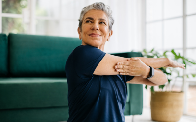 Happy and healthy senior woman doing a cross arm stretch in a peaceful yoga session at home