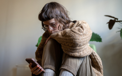 Lonely thoughtful teen girl spending free time at home alone scrolling news, photos in smartphone