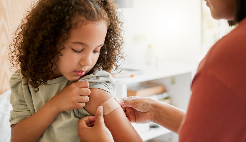 Nurse vaccinating child putting a bandage on at a clinic.