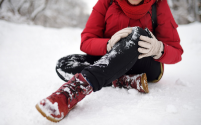 Person in snow holds leg as if in pain.