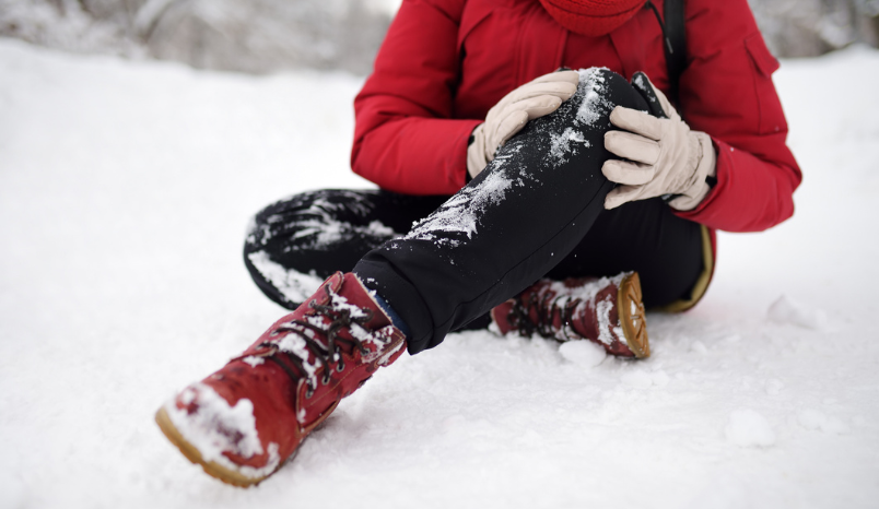 Person in snow holds leg as if in pain.
