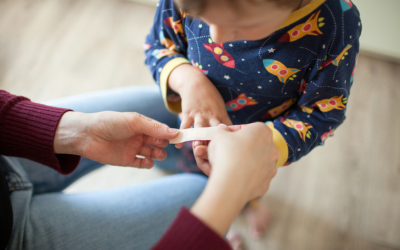 Parent places bandage over child's wound.