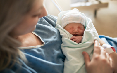 Mom in hospital gown holds newborn.