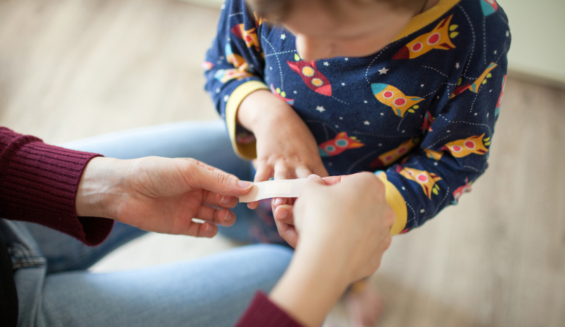 Parent places bandage over child's wound.