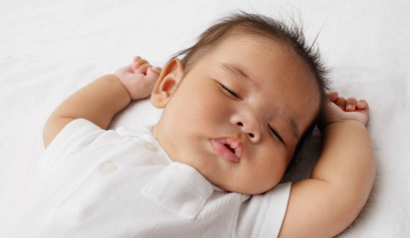 Newborn sleeps soundly on back.