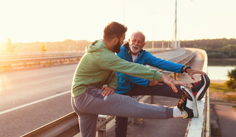 Two men in running clothes stretching after exercising outdoors