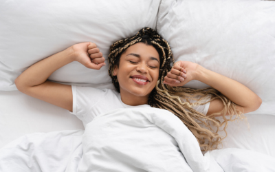 Woman stretches in bed, looking rested.