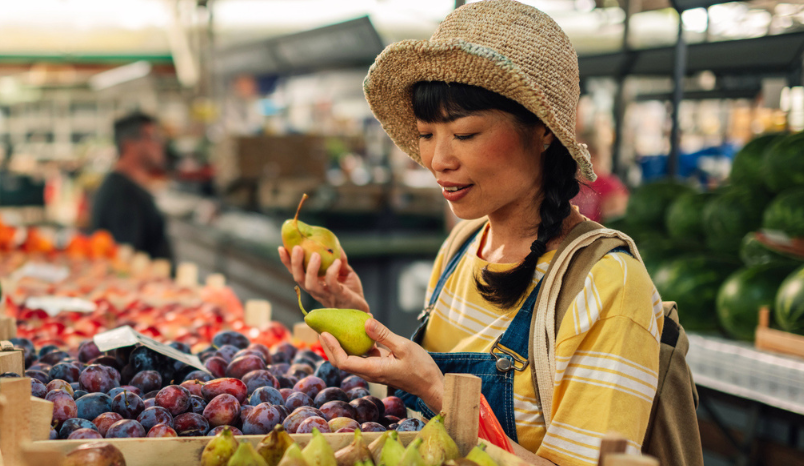 Woman looks at fruit at farmers market stall