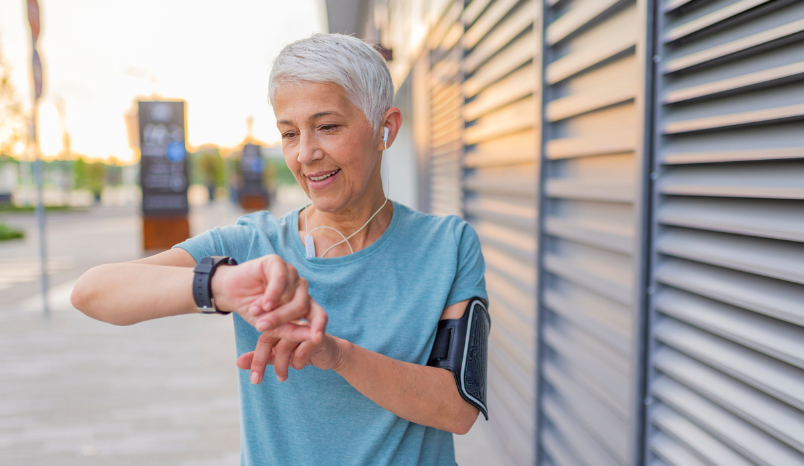 Athletic mature woman monitoring her running performance on smartwatch