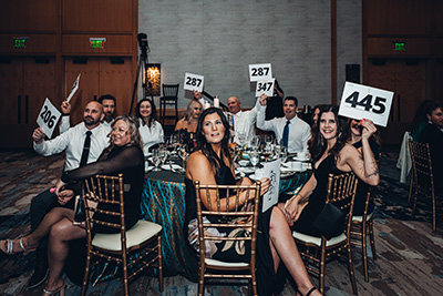 Bandage Ball 2026 event attendees sitting at table holding signs during auction