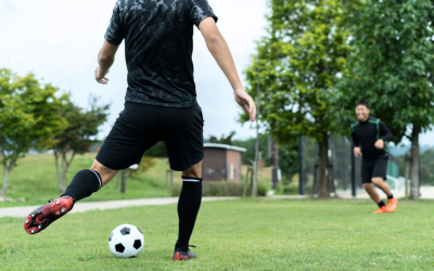Two men play soccer in park.
