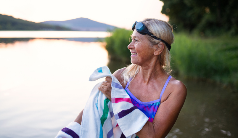 Portrait of active senior woman swimmer drying herself with towel outdoors by lake