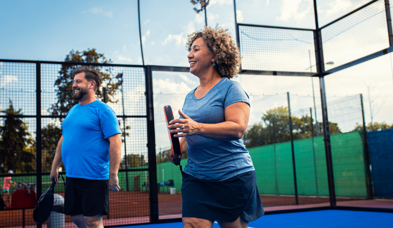 Woman and man on court playing game of pickleball.