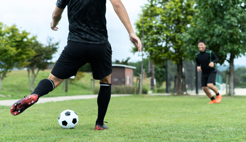Two men play soccer in park.