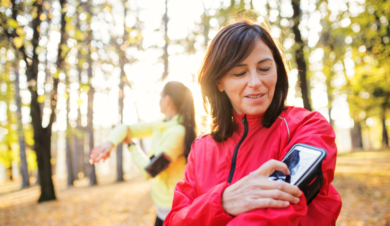 Woman in exercise clothing outside checking a health app on her phone.