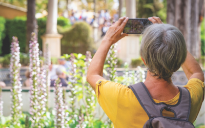 Woman takes pictures with cellphone outside while traveling.