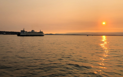 WA ferry on water with smoky orange sky.