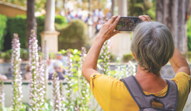 Older woman takes photo with her cellphone while traveling.