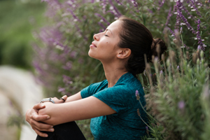 Person sitting quietly among flowering plants in an outdoor setting, reflecting in a peaceful natural environment.