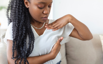Young African American woman examines breast over shirt.