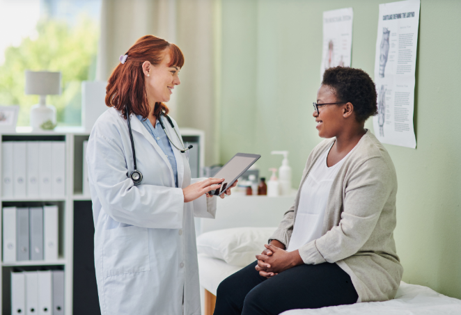Woman sitting on an examination table talking pleasantly with a healthcare provider.
