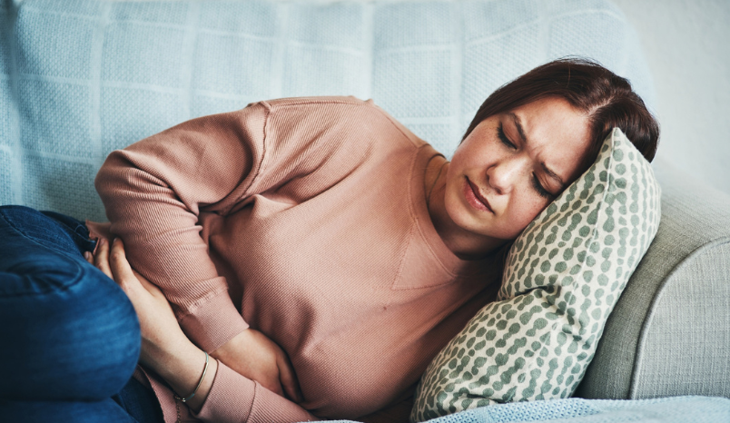 Shot of a young woman experiencing stomach pain while lying on the sofa at home