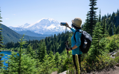  Woman taking photos of snow-capped Mount Rainier using smartphone.