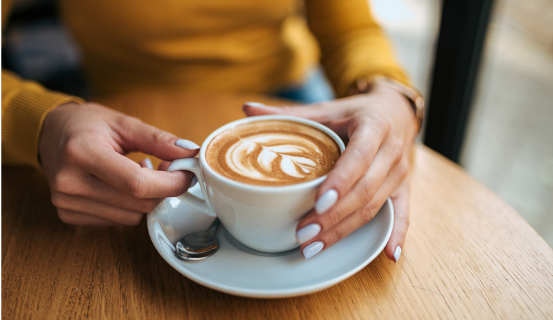 Close-up image of a female person drinking latte 
