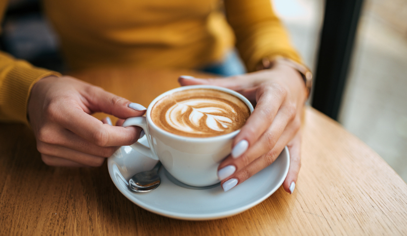 Person holds cappuccino. 