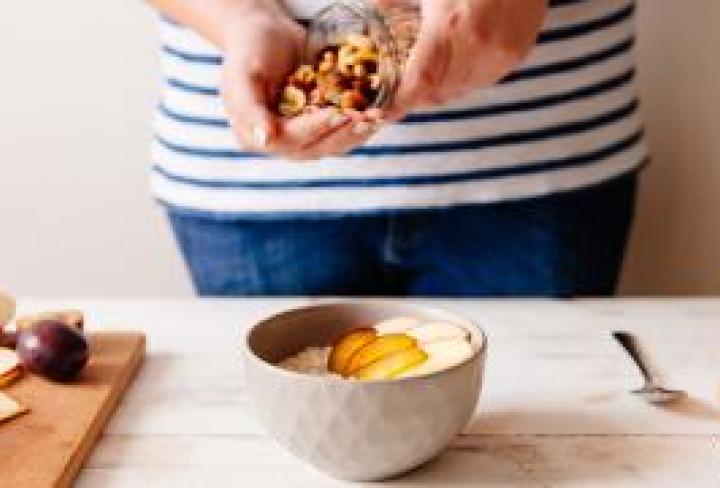 Person making a bowl of oatmeal and fruits