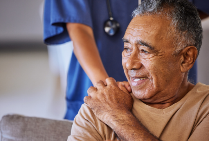 Older man holds the hand of a nurse.