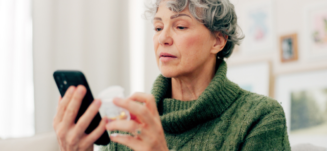 Woman looking at her phone holding supplement bottle.