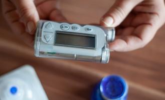 A person's hands holding an Insulin Pump 