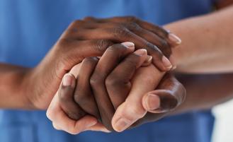 A healthcare professional holding the hand of a patient 