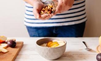 Person making a bowl of oatmeal and fruits