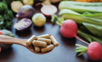 A spoonful of pills surrounded by fresh produce in the background