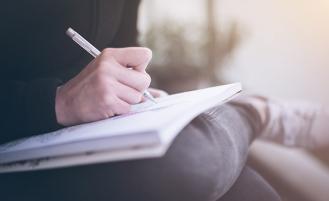 a person writing in their notebook with a pen