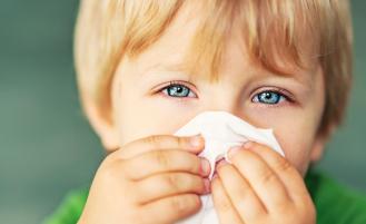 young-boy-holding-tissue-over-nose