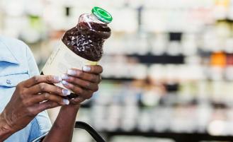 woman looking at label on juice bottle in grocery store