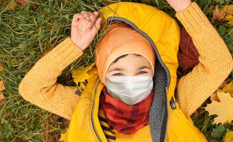 child-with-mask-on-ground-fall-leaves