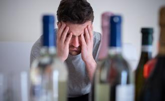 man-with-head-in-hands-alcohol-bottles